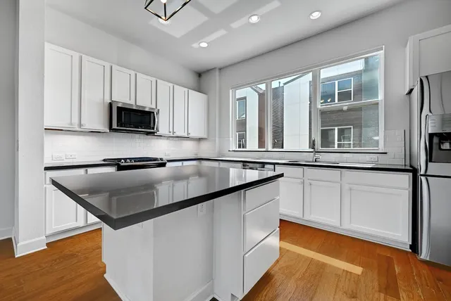 a kitchen with stainless steel appliances granite countertop a sink a stove and a refrigerator