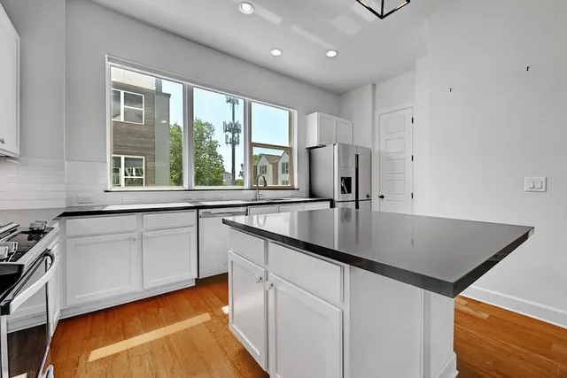 a kitchen with stainless steel appliances granite countertop a sink a stove and a refrigerator