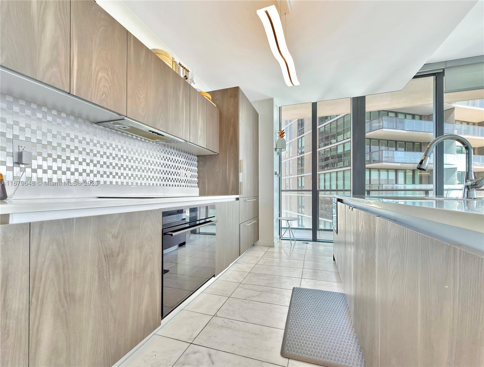 480 Northeast 31st Street, Unit 2407 Miami, FL 33137 - Photo 18 of 35 a kitchen with granite countertop a refrigerator a sink and dishwasher with a large window