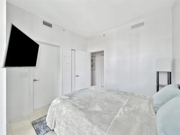 a bedroom with a bed tv and a window