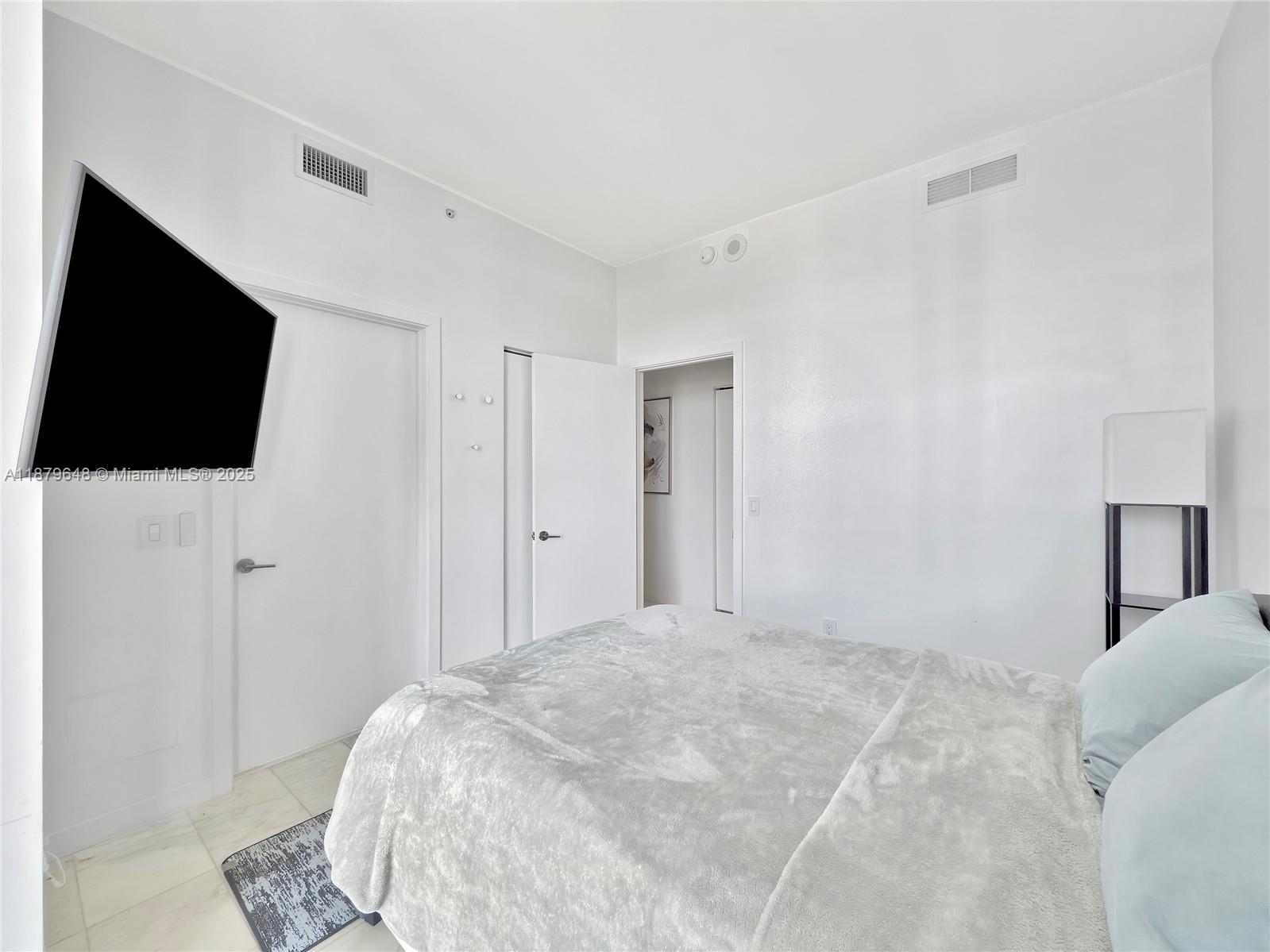 480 Northeast 31st Street, Unit 2407 Miami, FL 33137 - Photo 23 of 35 a bedroom with a bed tv and a window