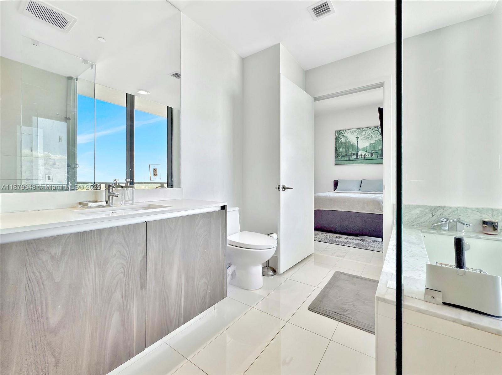 480 Northeast 31st Street, Unit 2407 Miami, FL 33137 - Photo 34 of 35 a spacious bathroom with a double vanity sink toilet mirror and bathtub