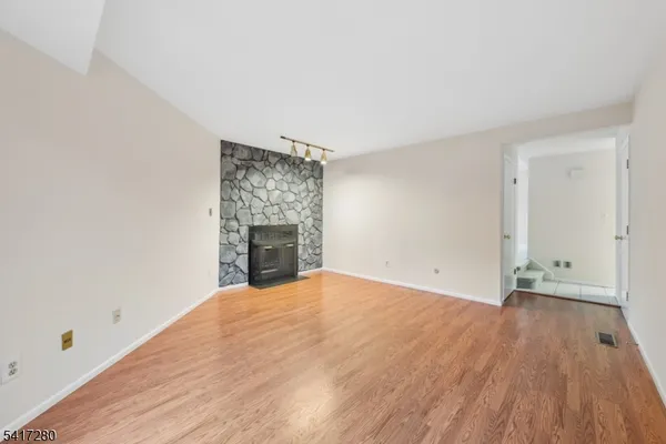 a view of a refrigerator in kitchen and an empty room in wooden floor