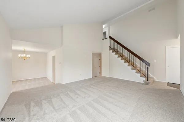 an empty room with a chandelier fan and wooden floor