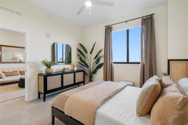 a bedroom with a bed table chair and a large mirror