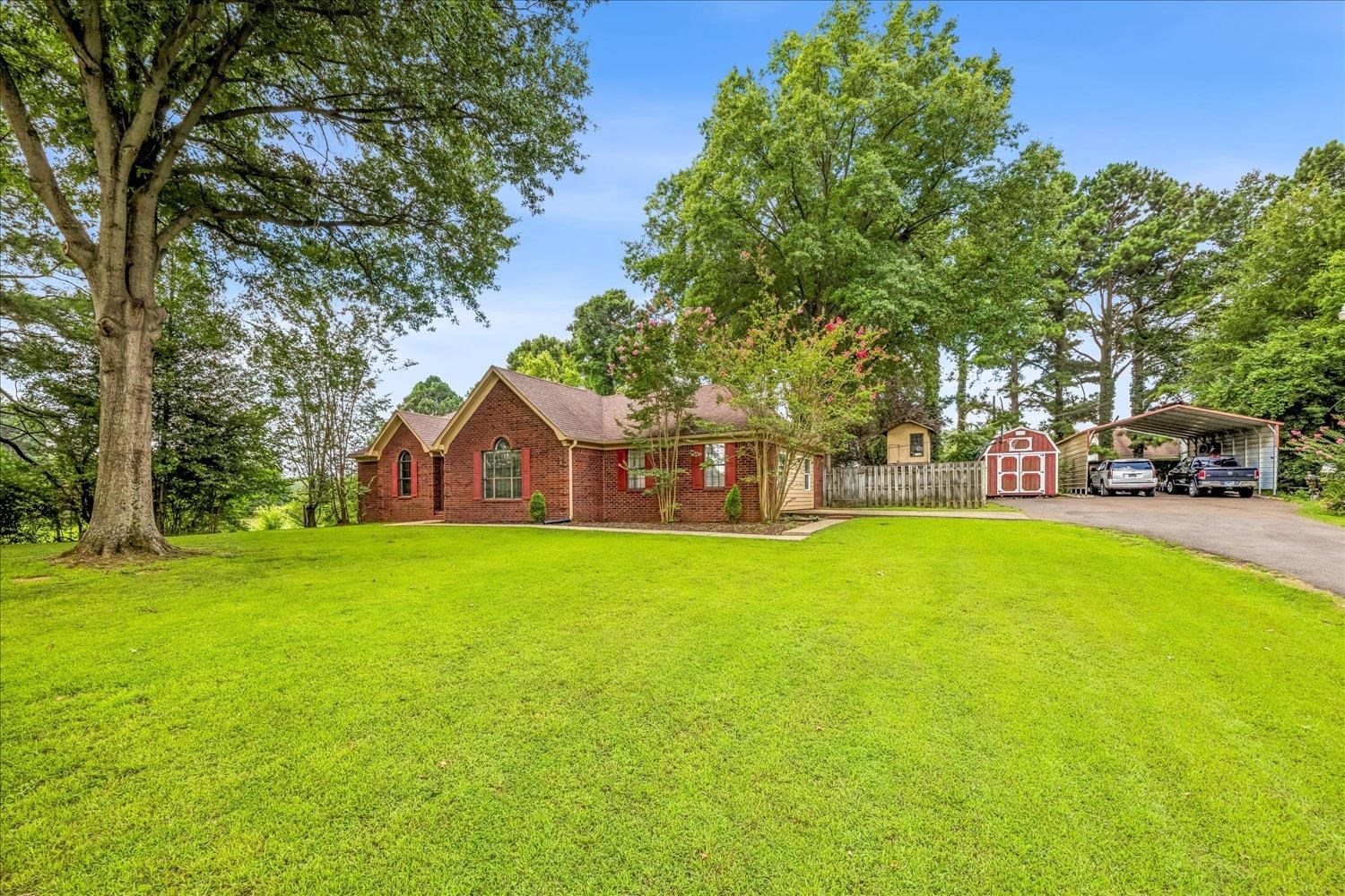 184 Cherokee Road Millington, TN 38053 - Photo 2 of 27 Expansive green lawn with mature trees and a brick-faced home