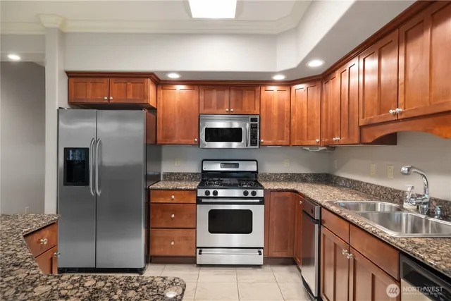 a kitchen with stainless steel appliances granite countertop a stove a refrigerator and a sink