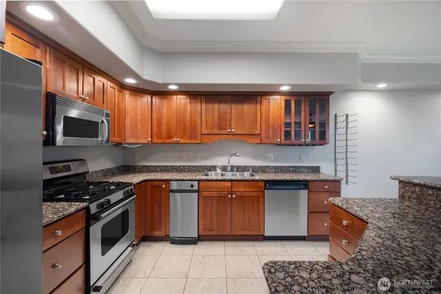 a kitchen with stainless steel appliances granite countertop a stove a sink and a microwave