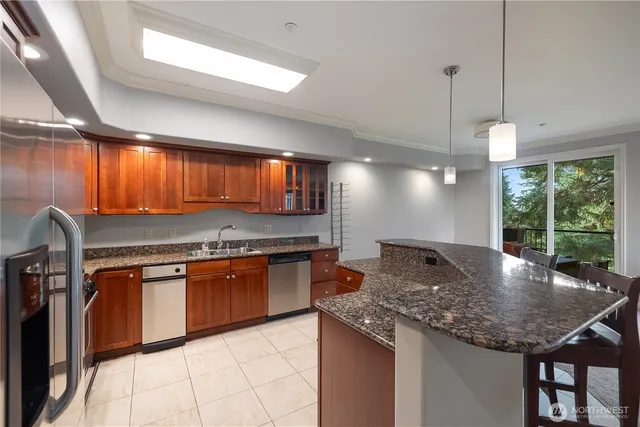 a kitchen with stainless steel appliances granite countertop a sink a stove and a wooden cabinets