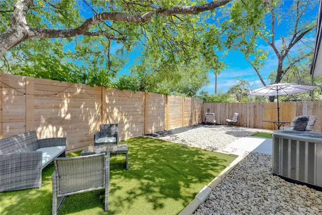 a view of a backyard with table and chairs potted plants and a large tree