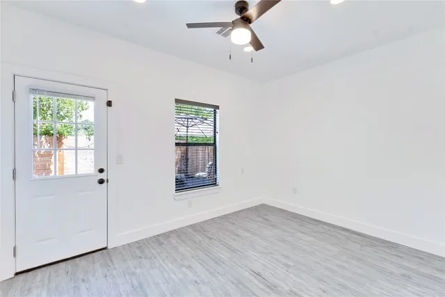 a view of empty room with wooden floor and fan
