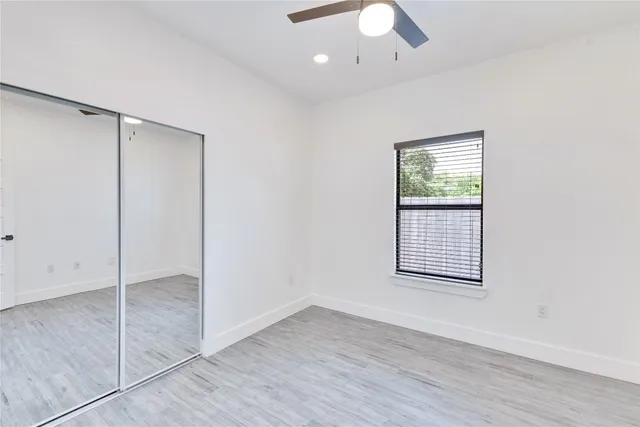 an empty room with wooden floor closet and windows