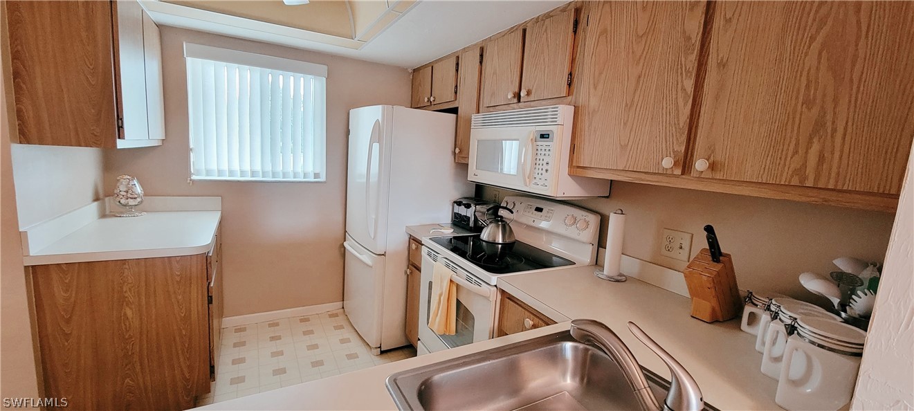 1022 Manatee Road, Unit D206 Naples, FL 34114 - Photo 8 of 21 a kitchen with a sink a refrigerator and cabinets