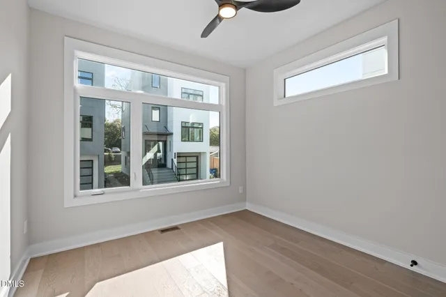 a view of an empty room with wooden floor and a window