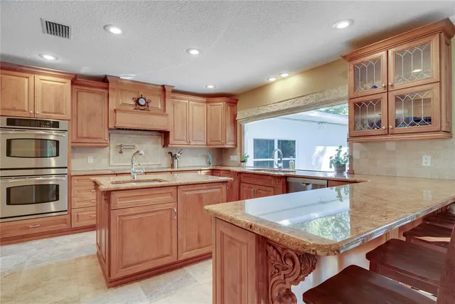 a kitchen with kitchen island granite countertop a stove top oven a sink a counter space and cabinets