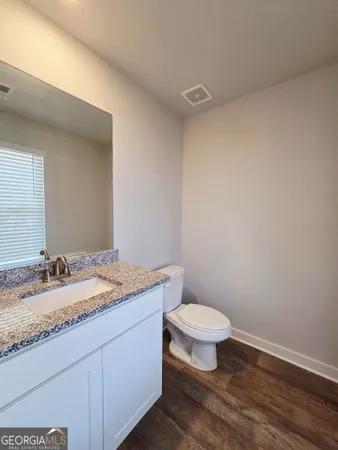 a bathroom with a granite countertop toilet a sink and a mirror