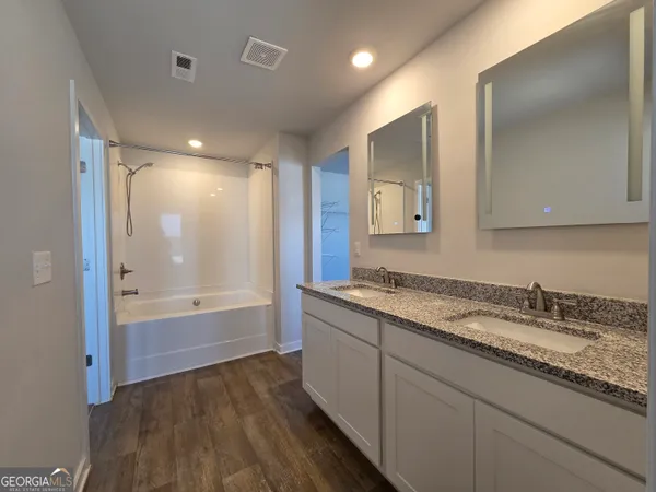 a bathroom with a granite countertop sink mirror and bathtub