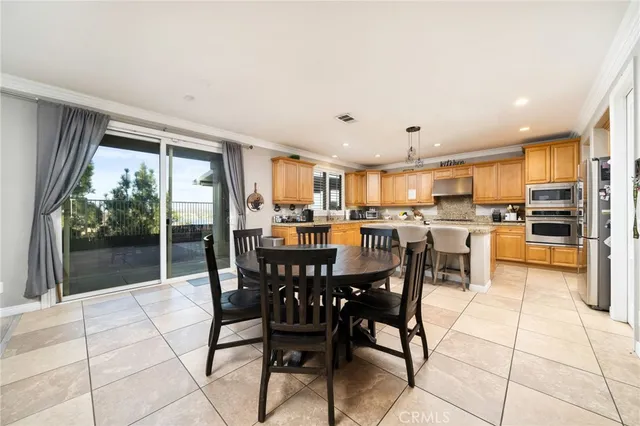 a kitchen with stainless steel appliances granite countertop a stove top oven a sink a dining table and chairs