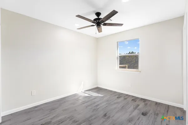 a view of a room with wooden floor and a ceiling fan