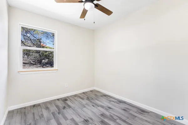 a view of an empty room with a window and wooden floor