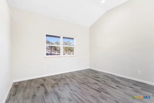 an empty room with wooden floor and window