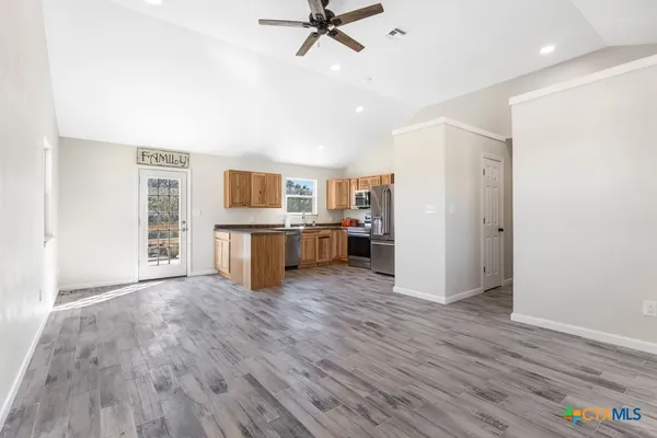 a view of kitchen with stainless steel appliances a stove top oven a refrigerator with white cabinets and wooden floor