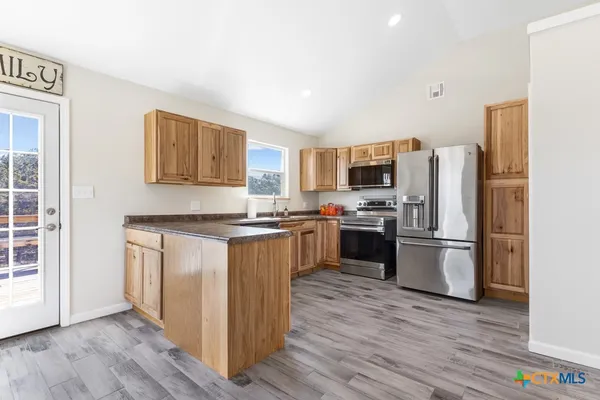 a kitchen with a refrigerator stove and wooden floor
