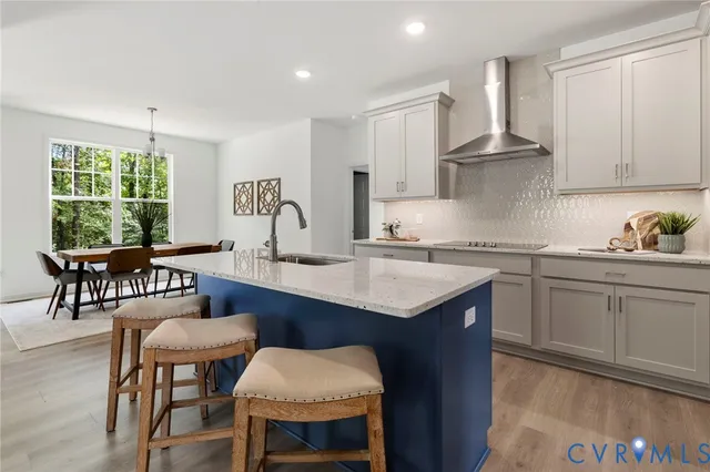 a kitchen with granite countertop a table chairs stove and white cabinets