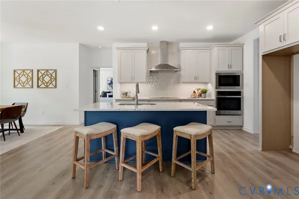 a kitchen with stainless steel appliances granite countertop a dining table chairs refrigerator and sink