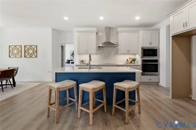 a kitchen with stainless steel appliances granite countertop a dining table chairs refrigerator and sink