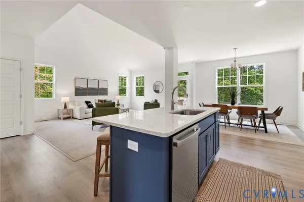 a open kitchen with stainless steel appliances granite countertop a stove top oven a sink dishwasher a dining table and chairs with wooden floor