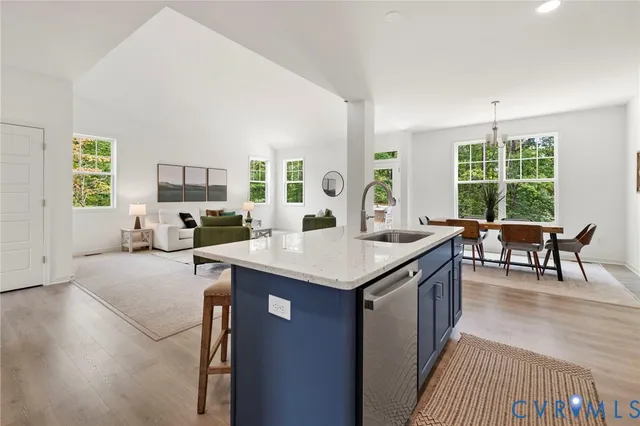 a open kitchen with stainless steel appliances granite countertop a stove top oven a sink dishwasher a dining table and chairs with wooden floor