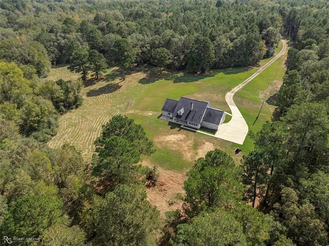 an aerial view of a house with a yard and trees all around