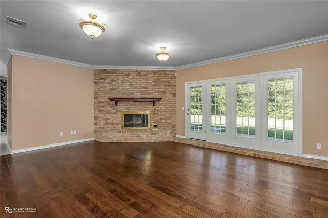 a view of empty room with wooden floor and fireplace
