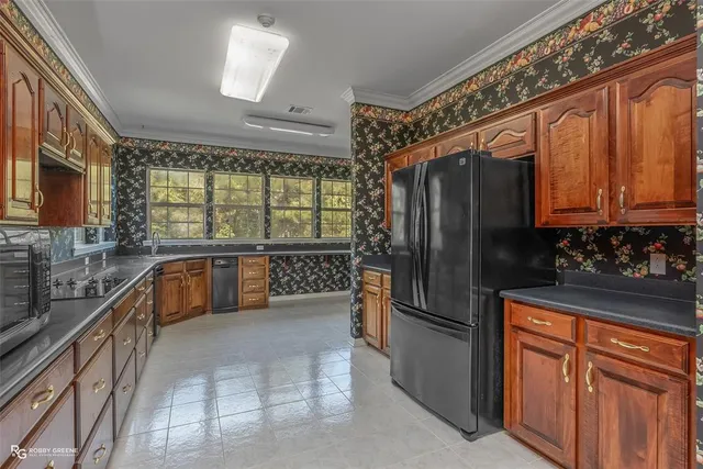 a kitchen with stainless steel appliances granite countertop a refrigerator a oven a sink with wooden cabinets and furniture