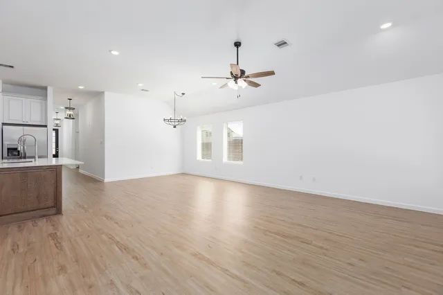 a view of a kitchen with a dishwasher a kitchen island hardwood floor and a ceiling fan