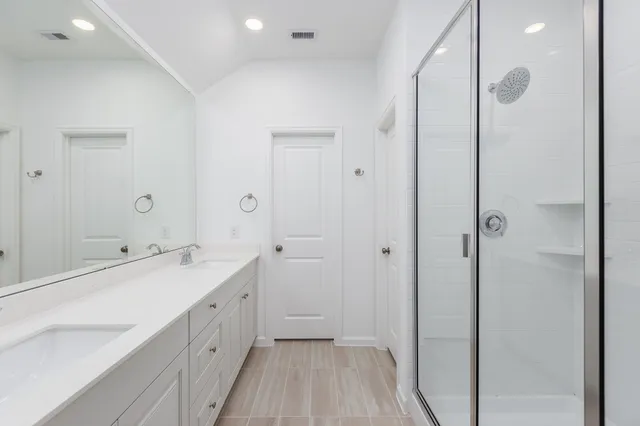 a spacious bathroom with a double vanity sink a mirror and shower