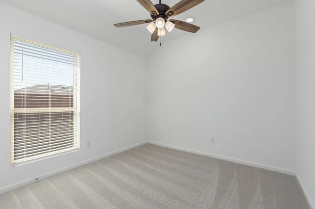 an empty room with a window and a fan
