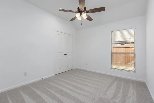 an empty room with a window and a fan