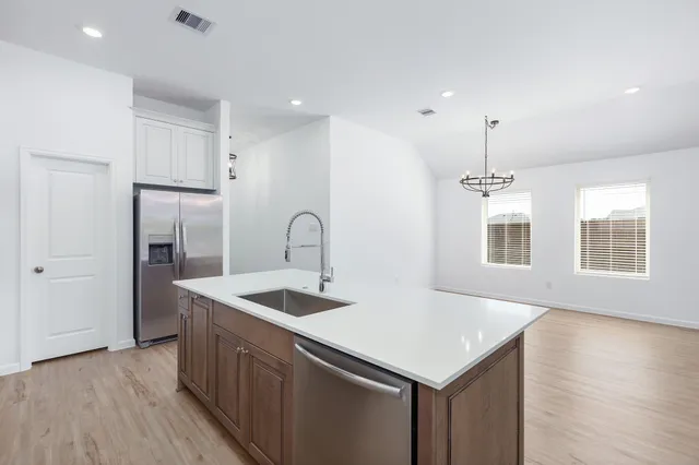 a kitchen with stainless steel appliances granite countertop a sink a refrigerator and a wooden floor