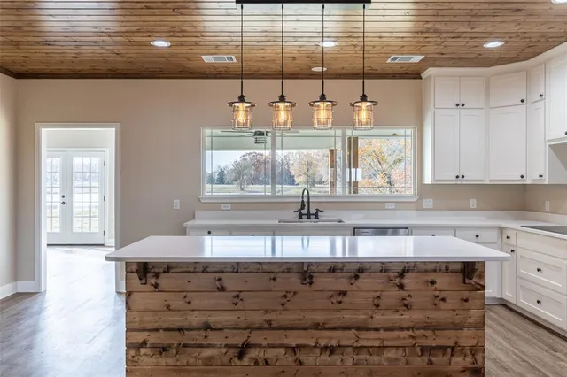a kitchen with kitchen island granite countertop a sink and a white wooden cabinets