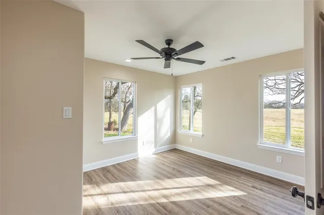 a view of an empty room with a window and wooden floor