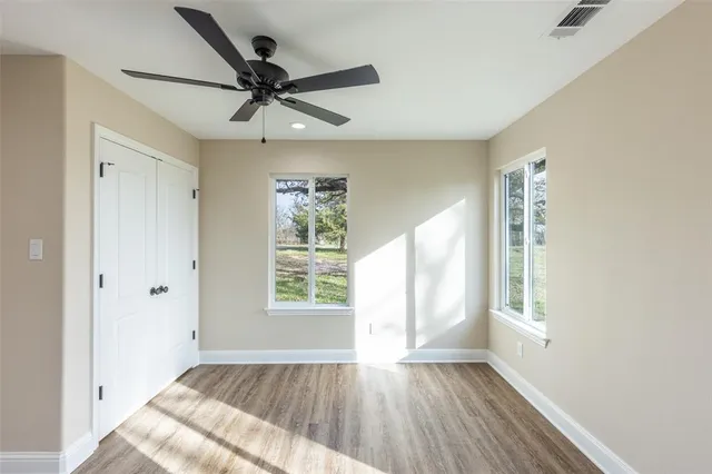 a view of empty room with wooden floor and fan