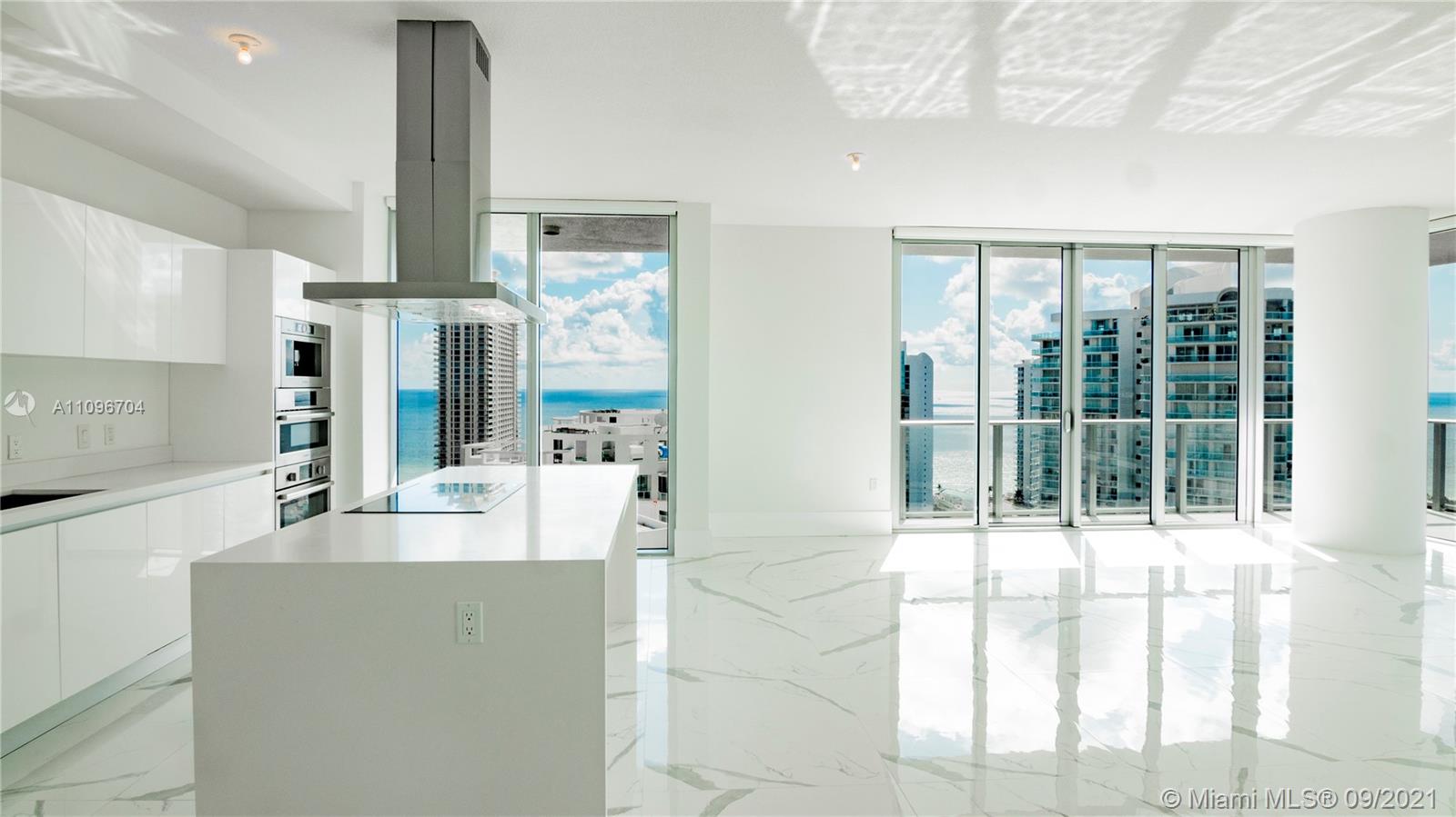 a large white kitchen with granite countertop a large window