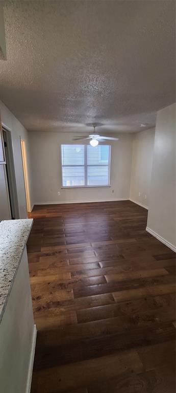 1907 Robbins Place, Unit 204 Austin, TX 78705 - Photo 3 of 7 Unfurnished dining area with a textured ceiling, dark wood-type flooring, and a ceiling fan
