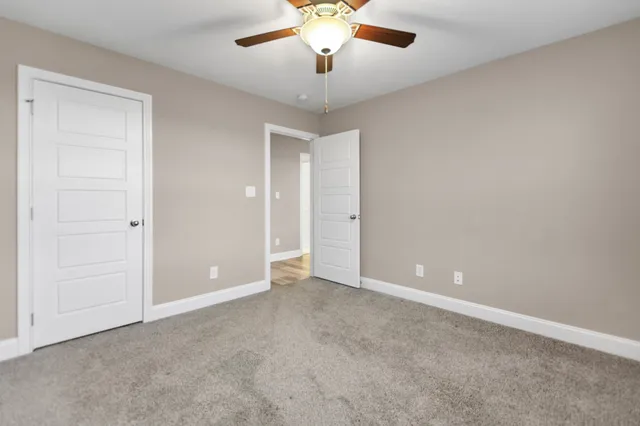 a view of an empty room with a chandelier fan