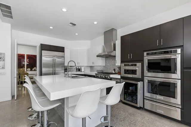 a large kitchen with stainless steel appliances granite countertop a stove top oven a sink dishwasher and white cabinets