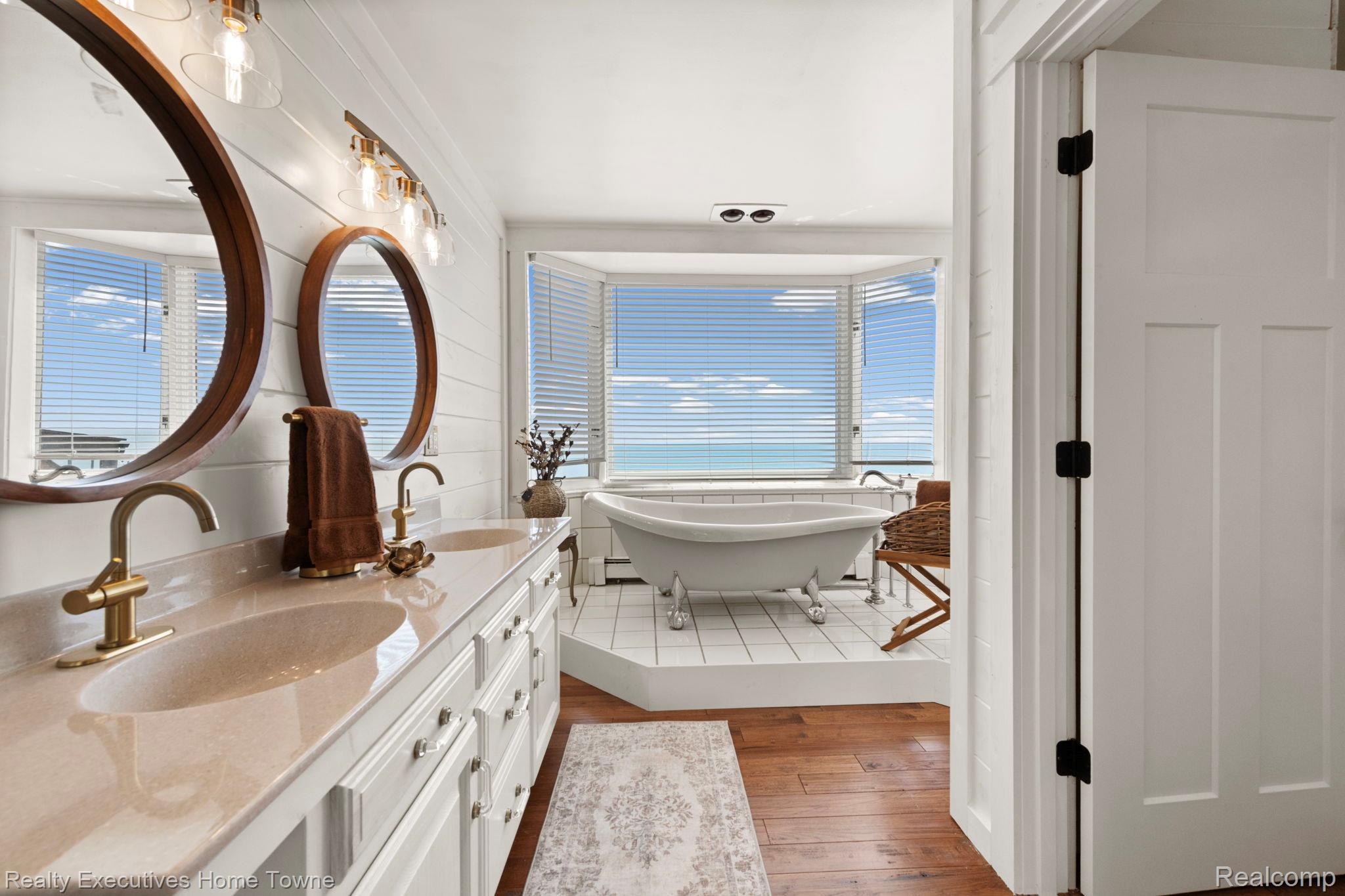 8308 Lakeshore Road Fort Gratiot, MI 48059 - Photo 64 of 79 Bathroom featuring a dual vanity with undermount sinks and brass-finish faucets, set against a shiplap accent wall