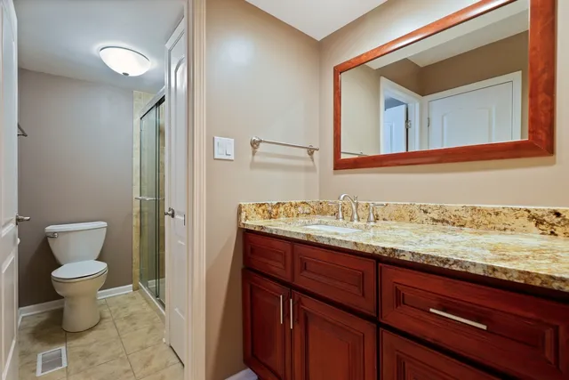 a bathroom with a granite countertop sink and a toilet