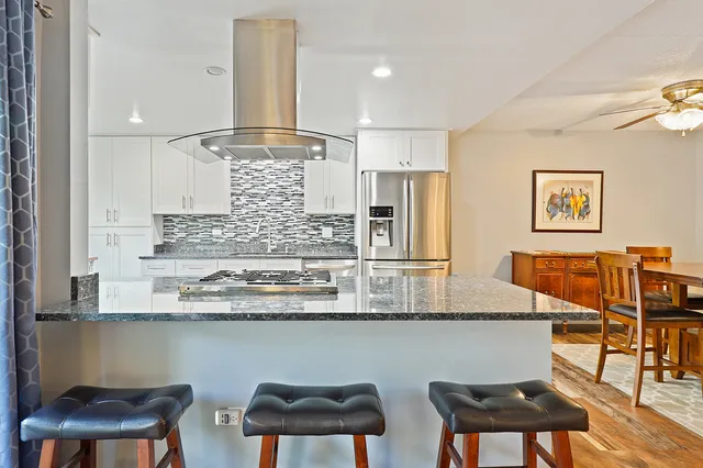 a kitchen with stainless steel appliances granite countertop a table chairs sink and cabinets